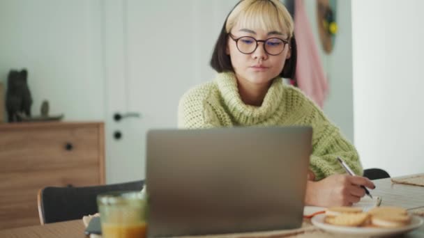 Gözlüklü Meditasyon Yapan Asyalı Kadın Evdeki Bilgisayarından Defterine Bir Şey — Stok video