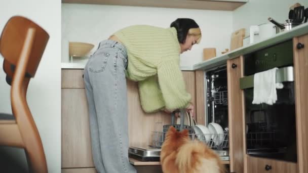 正のアジアの女性は自宅で食器洗い機から料理を取る — ストック動画