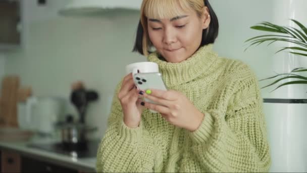 Mulher Asiática Positiva Olhando Para Telefone Para Lado Casa — Vídeo de Stock