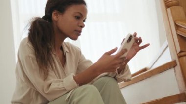 Düşünceli Afrikalı kadın evdeki telefonda bant yapıştırıyor.