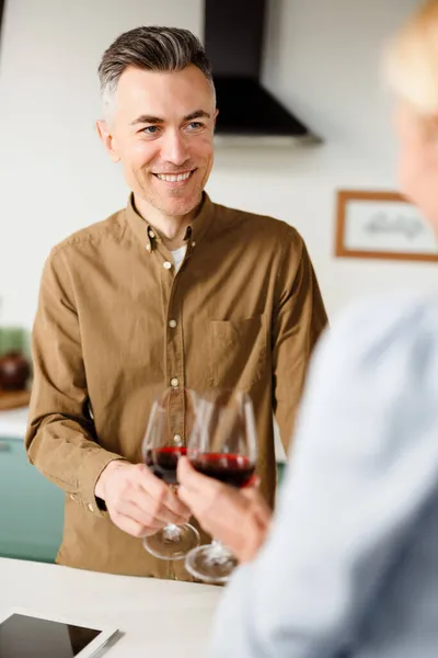 Χαμογελώντας Μεσήλικες Ζευγάρι Πίνοντας Κόκκινο Κρασί Στην Κουζίνα Στο Σπίτι — Φωτογραφία Αρχείου