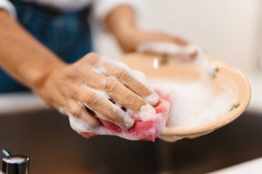 Beyaz kadın mutfakta bulaşık yıkıyor.