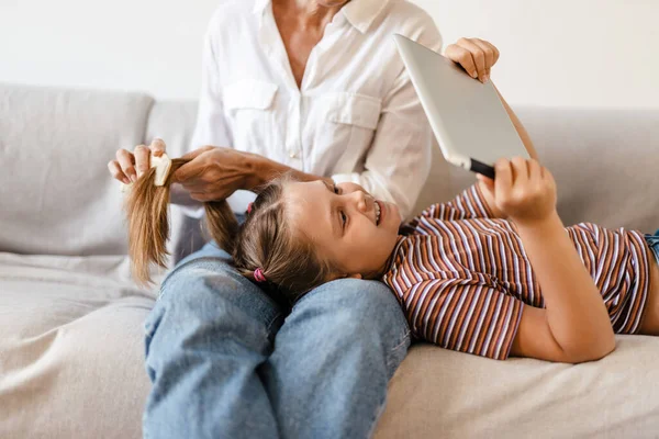 Annesi Evde Saçını Tararken Beyaz Kız Tablet Bilgisayar Kullanıyor — Stok fotoğraf