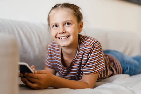 White Preteen Girl Smiling Using Mobile Phone While Lying Couch — Stock Photo, Image