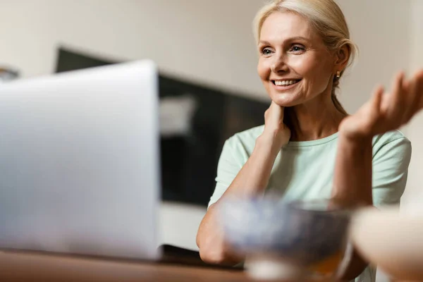 Mujer Madura Rubia Haciendo Gestos Utilizando Ordenador Portátil Mientras Almuerza — Foto de Stock