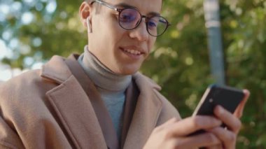Parkta telefonla mesajlaşan olumlu Arap adam.