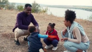 Nehir kenarında frizbi oynayan mutlu Afrikalı bir aile.