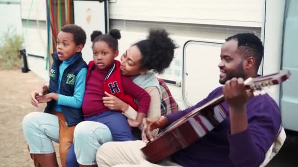 Счастливый Африканский Отец Играет Гитаре Своей Семьи Возле Трейлера — стоковое видео
