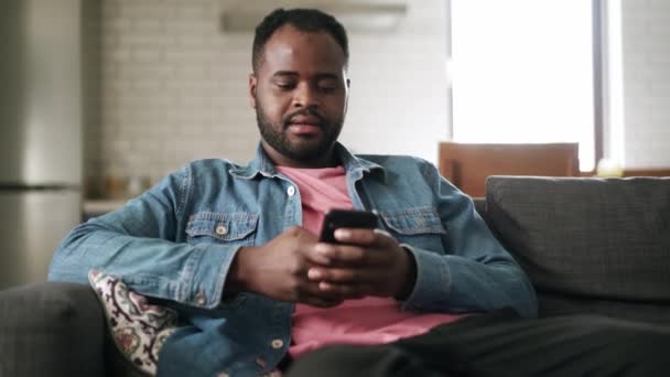 Afrikanskt Leende Man Messar Telefon Hemma Soffan — Stockvideo
