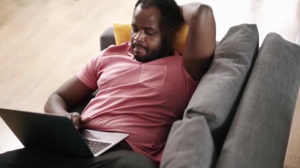 Leende Afrikansk Man Skriva Med Laptop Soffan — Stockvideo