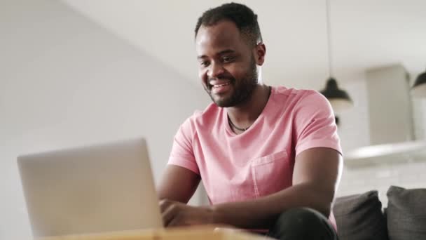 Afrikanischer Positiver Mann Tippt Etwas Laptop Und Schreibt Hause Auf — Stockvideo
