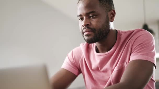 ソファの上でノートパソコンでビデオ通話で話しているアフリカの有能な男 — ストック動画
