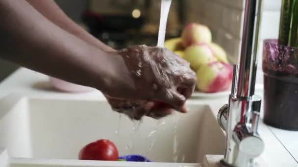 アフリカの男は流しの台所でトマトを洗う — ストック動画
