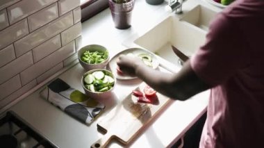 Adam mutfakta salata için tahtada sebze kesiyor.