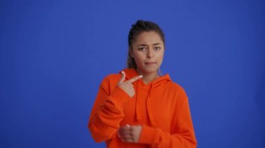 Saçları örgülü kızgın Afrikalı bir kadın mavi stüdyoda bana jest yapmıyor.