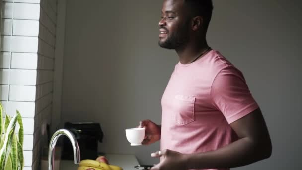 Homem Africano Positivo Bebendo Chá Olhando Para Telefone Cozinha — Vídeo de Stock