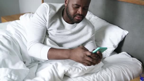 Sleepy Hombre Africano Mensajes Texto Por Teléfono Cama — Vídeo de stock