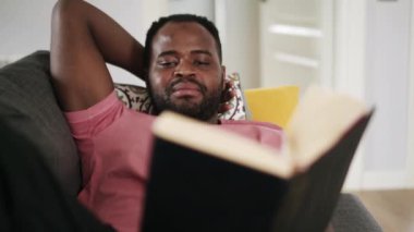 Koltukta kitap okuyan kendinden emin bir Afrikalı.