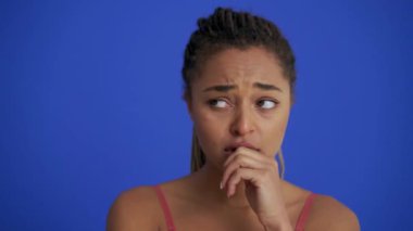 Saçları örgülü Afrikalı üzgün kadın mavi stüdyoda bir şey için endişeleniyor.