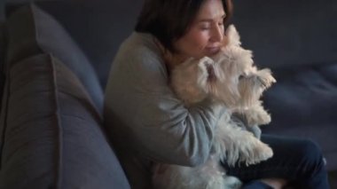 Olgun bir kadının evde köpeğini kucaklaması.