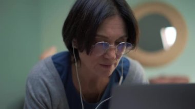 Yatakta dizüstü bilgisayarla mesaj atan olgun bir kadın.