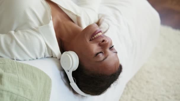 Glimlachende Afrikaanse Vrouw Luisteren Muziek Hoofdtelefoon Het Bed — Stockvideo