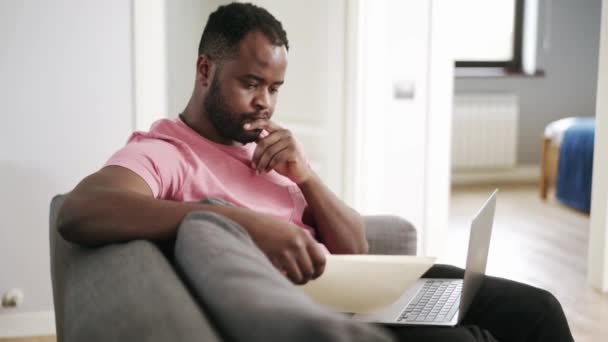 Αφρικανός Σκεπτικός Άντρας Που Κοιτάζει Την Εφημερίδα Στο Σπίτι Στον — Αρχείο Βίντεο