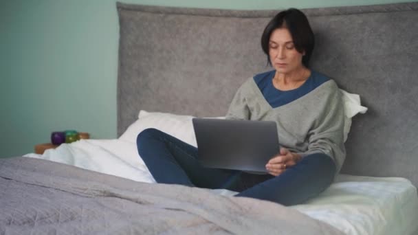 Poważny Dojrzałe Kobieta Wpisując Przez Laptop Łóżku — Wideo stockowe