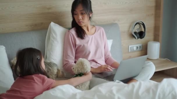 Koncentrerad Asiatisk Mamma Arbetar Laptop Medan Hennes Dotter Stroking Hund — Stockvideo