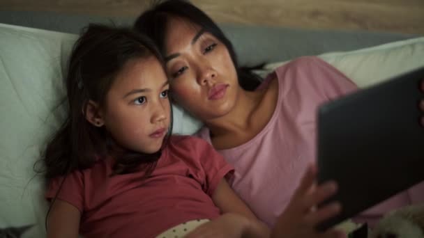 Pensiv Asiatisk Mor Och Dotter Tittar Tabletten Sängen — Stockvideo