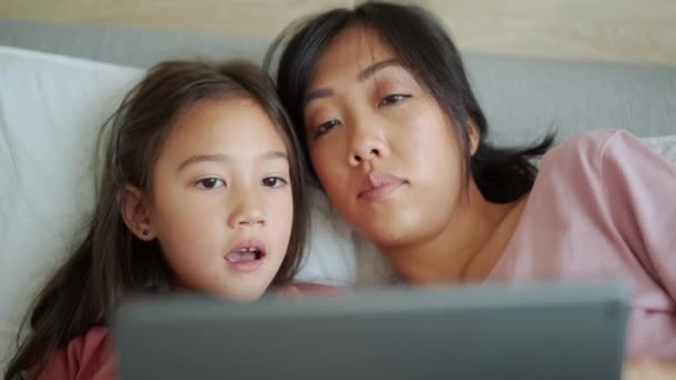 Düşünceli Asyalı Anne Kız Tablete Bakıyor Yatakta Konuşuyor — Stok video