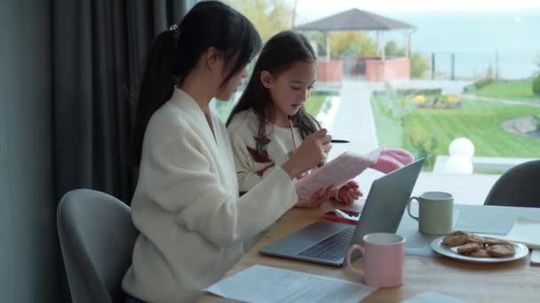 Позитивна Азіатська Мати Працює Над Ноутбуком Дочка Робить Домашнє Завдання — стокове відео
