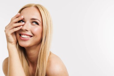 Beyaz arka planda yarı çıplak, gülen ve yüzünü kapatan sarışın kadın.