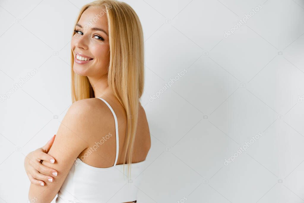Young blonde woman smiling while looking at camera isolated over white background
