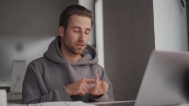 Kapüşonlu ciddi bir adam bilgisayarla konuşuyor ve ofisteki parmaklarını sayıyor.