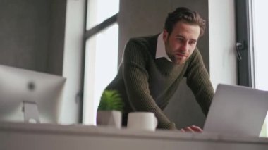 Ofiste dizüstü bilgisayarda bir şey arayan neşeli adam