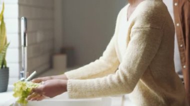 Babası kızına marul yapraklarını nasıl yıkayacağını öğretiyor.