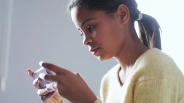 Meditasyon yapan Afrikalı kız evde telefonla mesaj atıyor.