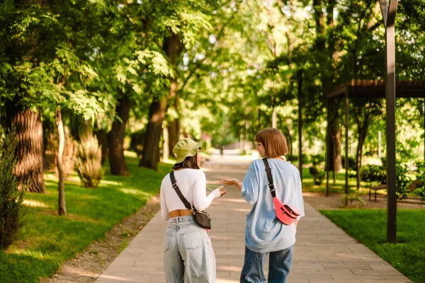 Multiracial Två Kvinnor Pratar Och Gester När Går Tillsammans Grön — Stockfoto