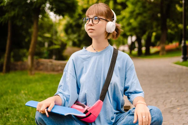 Jovem Mulher Branca Ouvindo Música Com Fones Ouvido Enquanto Sentada — Fotografia de Stock