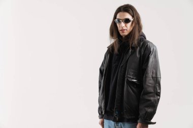 Deri ceketli genç, modaya uygun beyaz adam beyaz arka plan üzerinden kameraya bakıyor.