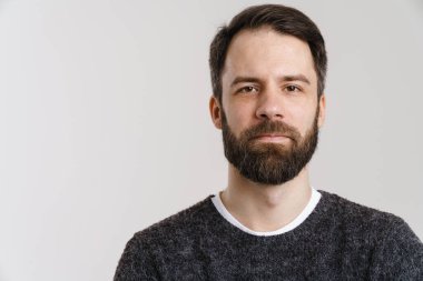 Beyaz, beyaz arka planda sakallı bir adam poz veriyor ve kameraya bakıyor.