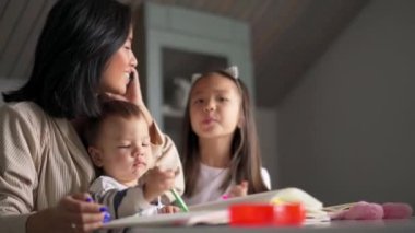 Mutlu Asyalı anne telefonla konuşuyor ve mutfakta çocuklara bakıyor.