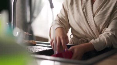 Kadın elleri mutfakta bulaşık yıkıyor.