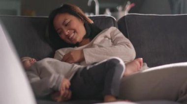 Gülümseyen anne oğluyla kanepede yatıyor.