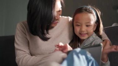 Mutlu anne ve kız tablete bakıyor.