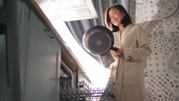 亚洲女人在洗碗机里洗完后 用干布擦拭着一只煎锅 — 图库视频影像