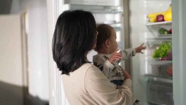 Asiática Mamá Sosteniendo Bebé Sus Brazos Sacando Algo Nevera — Vídeo de stock