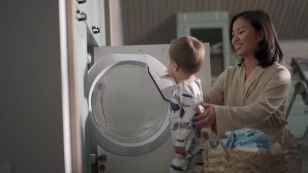Χαμογελώντας Ασιάτισσα Μαμά Και Γιος Βάζουν Πράγματα Στο Πλυντήριο — Αρχείο Βίντεο