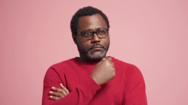 Düşünceli yetişkin Afrikalı adam pembe stüdyoda olumlu cevap veriyor.